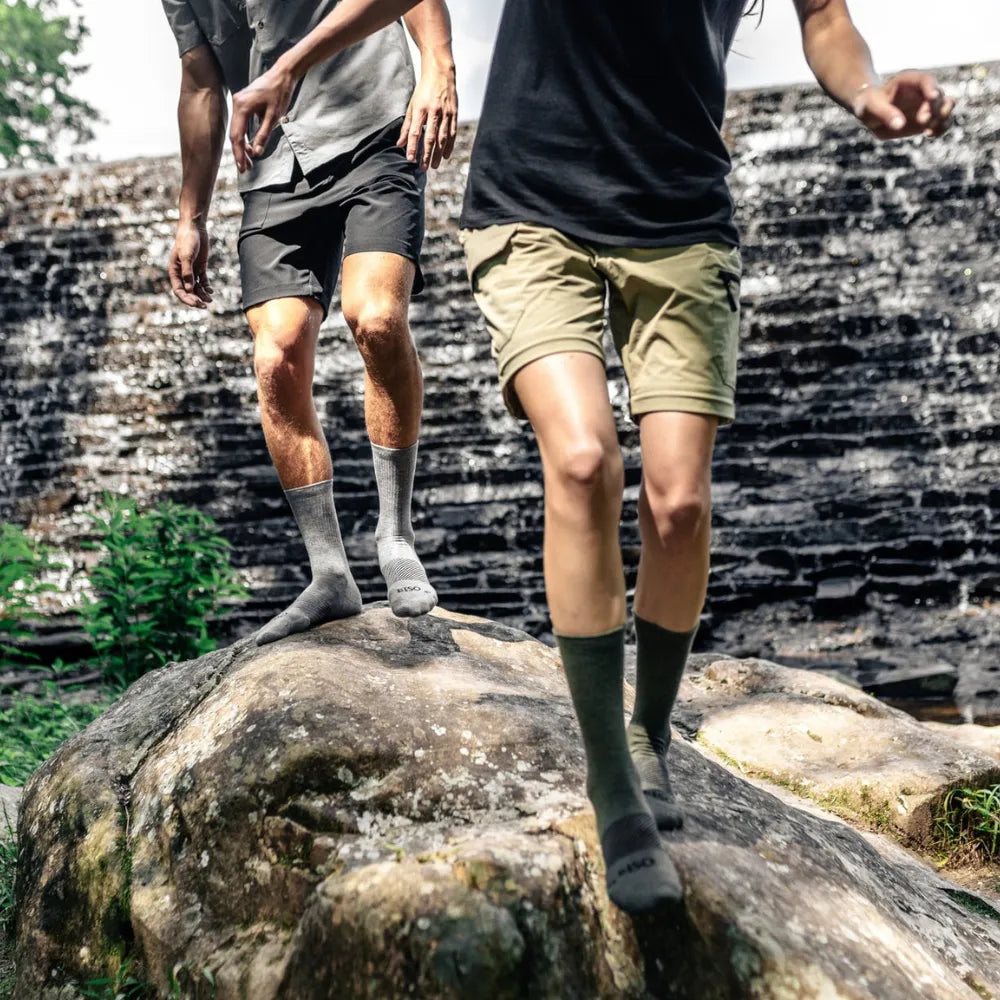 two people climbing rocks near waterfall in crew length wicked comfort merino wool socks | OS1st