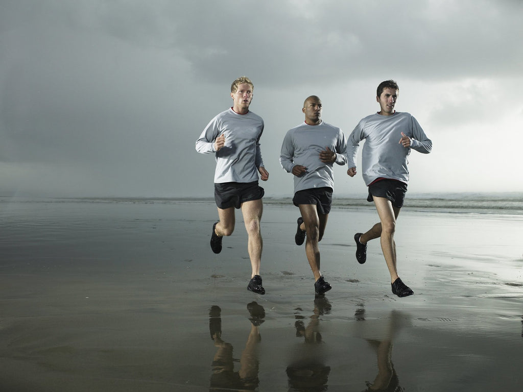 three men running along the shore 