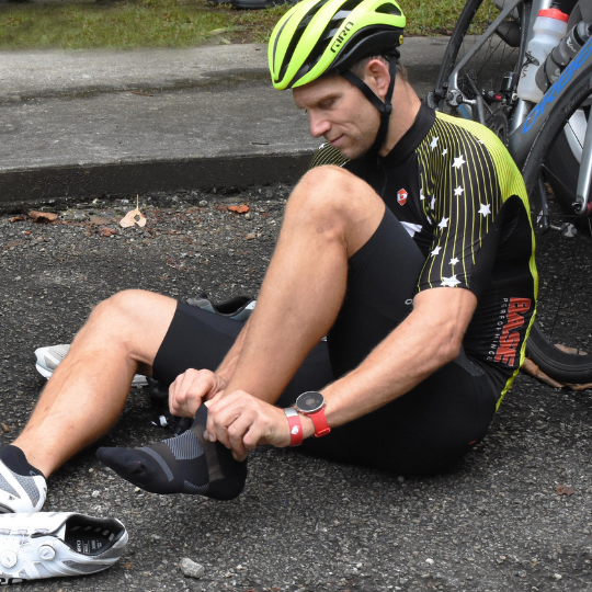 a man putting on his OS1st socks before going cycling 