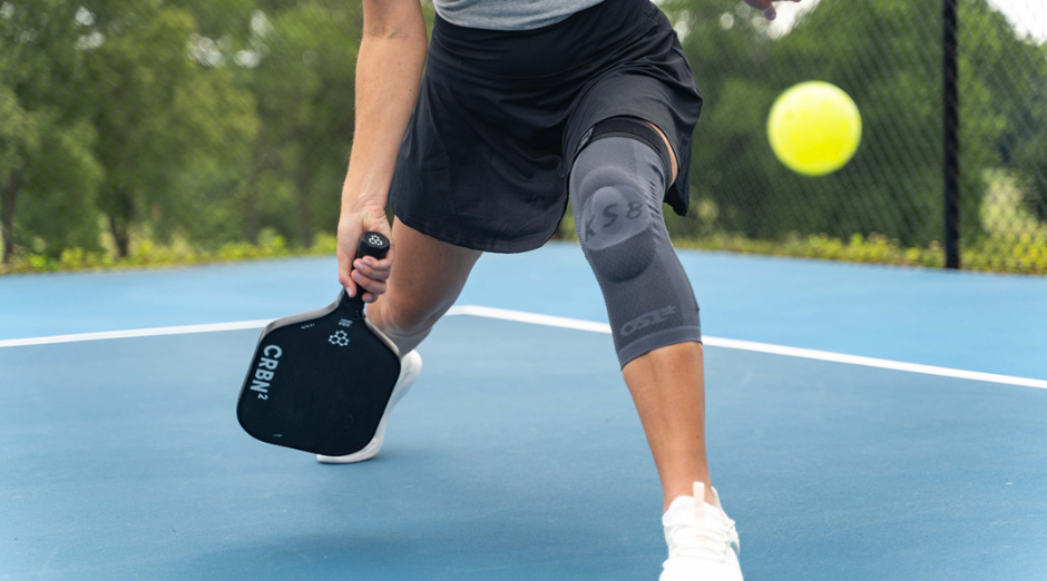 Woman plays pickleball while wearing an OS1st knee sleeve and socks