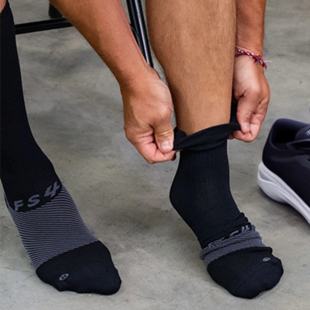 man putting on black crew plantar fasciitis socks | OS1st