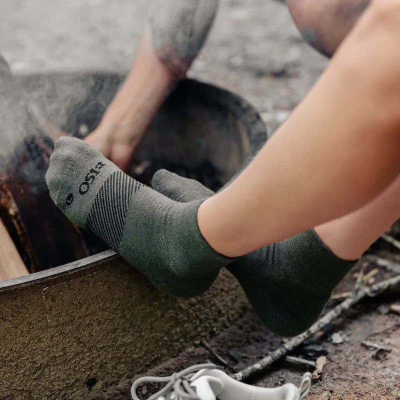 person sitting by campfire wearing quarter crew hunter green wicked comfort merino wool socks | OS1st