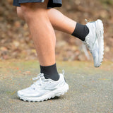 person running on a trail wearing quarter crew wicked comfort socks in black | OS1st