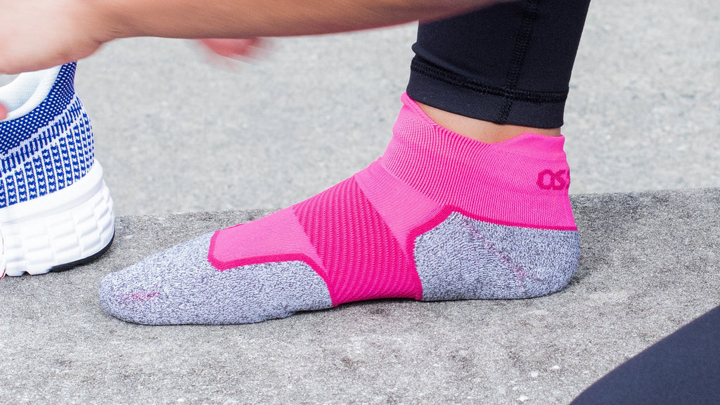 Woman wearing pink Active Comfort socks while putting her shoes on