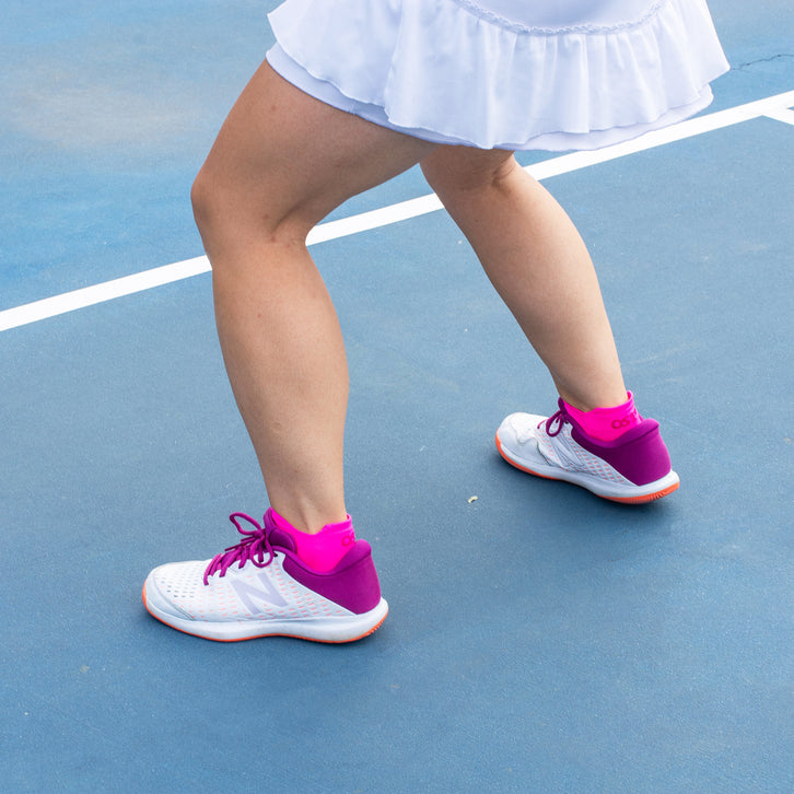 a woman playing tennis while wearing the pink fusion no show pickleball socks